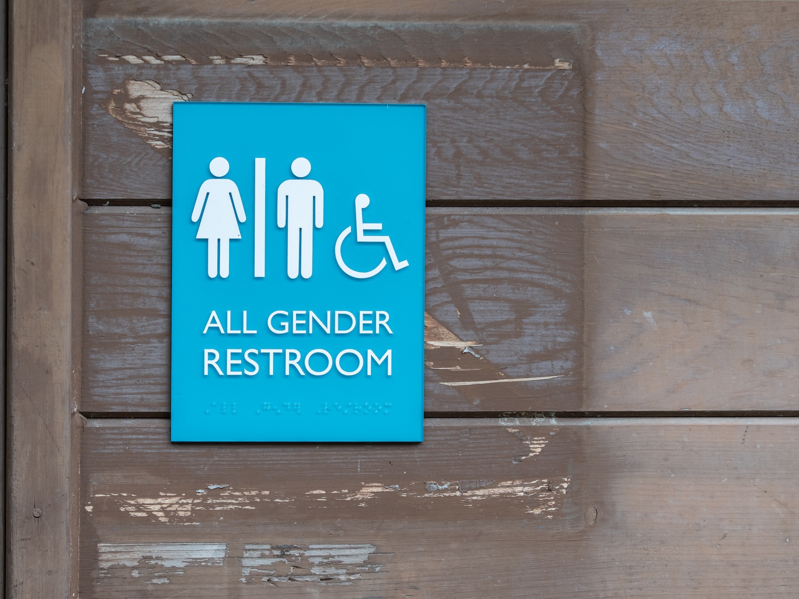 All gender restroom sign with Braille code on the side of the building.